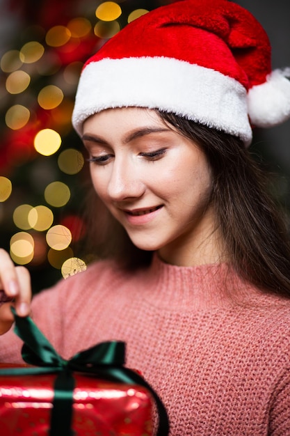 Una ragazza con un cappello da Babbo Natale con doni sullo sfondo degli interni di Capodanno.