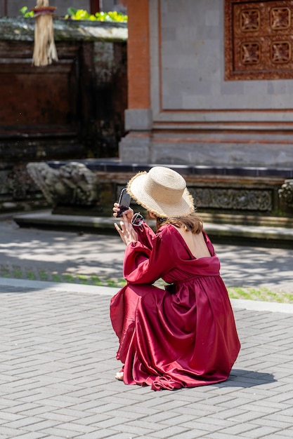 Una ragazza con un cappello di paglia fotografata sull'architettura del telefono nella città di Ubud, isola di Bali, Indonesia. L'isola di Bali è una popolare destinazione turistica.