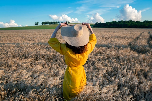 Una ragazza con un cappello di paglia in un campo di grano...