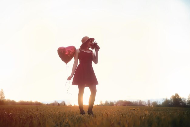 Una ragazza con un cappello durante una passeggiata nel parco. Una ragazza con un cesto cammina in autunno. La ragazza sta camminando lungo la strada al tramonto.