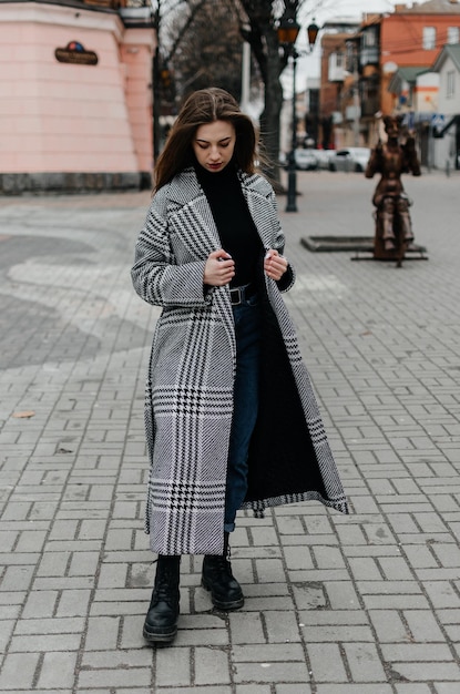 una ragazza con un cappotto cammina per la città