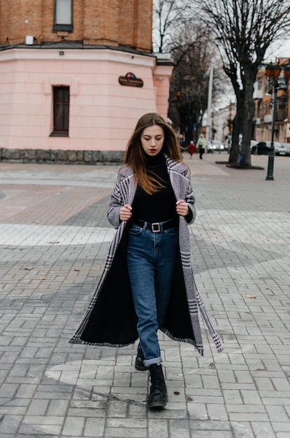 una ragazza con un cappotto cammina per la città