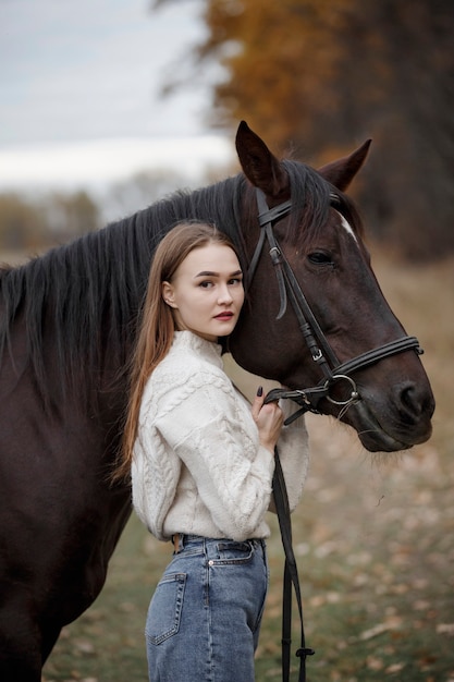 Una ragazza con un cavallo nella natura, una passeggiata autunnale con un animale