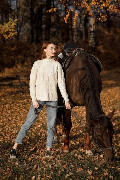 Una ragazza con un cavallo nella natura, una passeggiata autunnale con un animale