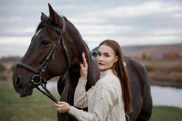 Una ragazza con un cavallo nella natura, una passeggiata autunnale con un animale