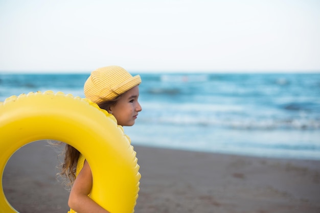 Una ragazza con un cerchio gonfiabile giallo in riva al mare Rilassarsi sul viaggio estivo in spiaggia