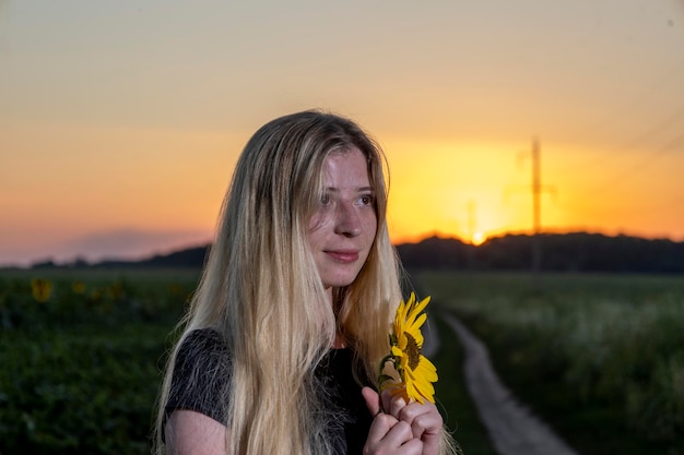 Una ragazza con un girasole sullo sfondo del tramonto