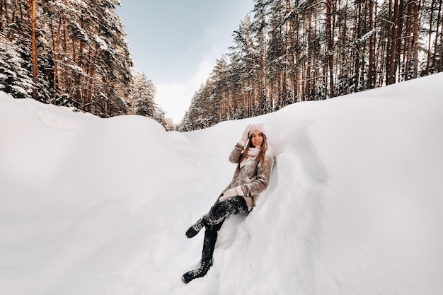 Una ragazza con un maglione e guanti in inverno si trova su una coperta di neve