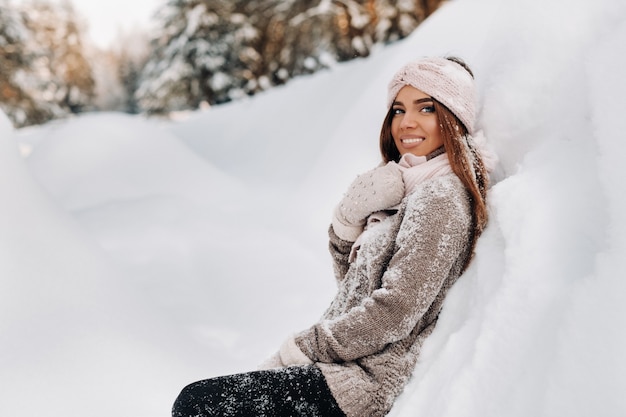 Una ragazza con un maglione e guanti in inverno si trova su uno sfondo innevato.