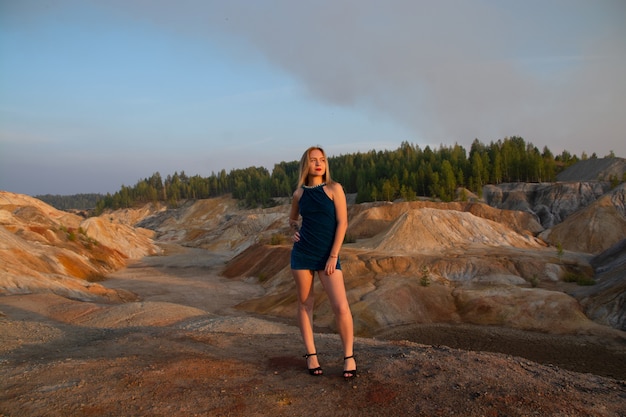 Una ragazza con un tatuaggio in un vestito blu in cima a una montagna. cava e montagne di argilla