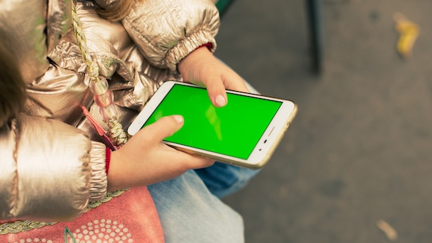 Una ragazza con un telefono sullo schermo chromakey verde strada