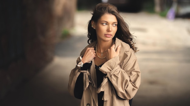 Una ragazza con un trench alla moda passeggia nel centro storico