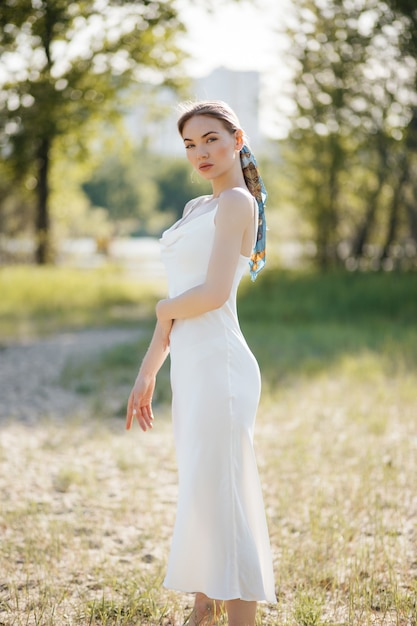 Una ragazza con un vestito bianco chiaro in posa nel parco