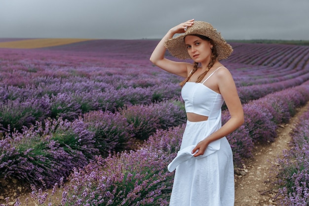 Una ragazza con un vestito bianco e un cappello di paglia in un campo di lavanda