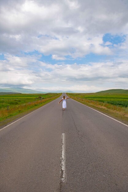Una ragazza con un vestito bianco sta camminando lungo una strada pittoresca