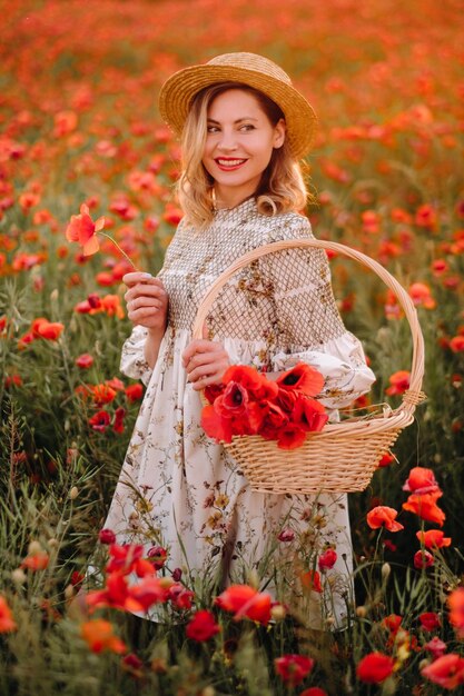 Una ragazza con un vestito con un cappello e con un cesto in un campo di papaveri
