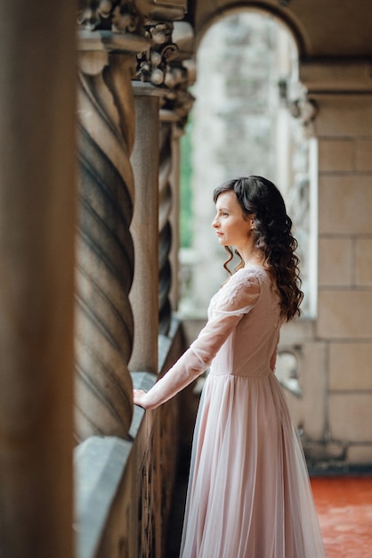 Una ragazza con un vestito rosa chiaro sullo sfondo di un castello medievale in pietra polacca