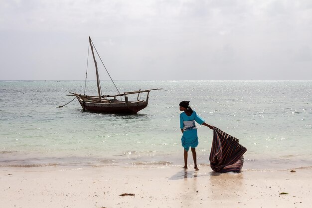 Una ragazza con una borsa grande si trova sull'oceano. Zanzibar