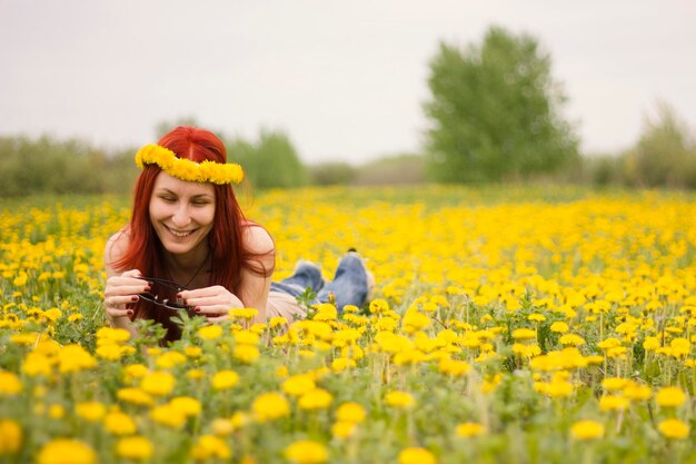 Una ragazza con una ghirlanda in testa, sdraiata sul campo, si metterà gli occhiali da sole