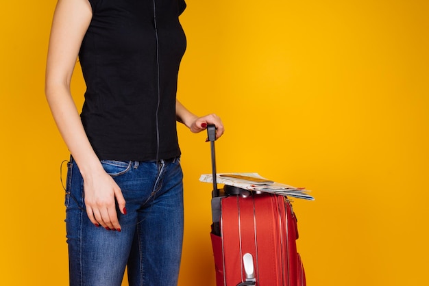 Una ragazza con una maglietta nera fa un giro del mondo in vacanza, con una valigia rossa, in attesa dell'aereo