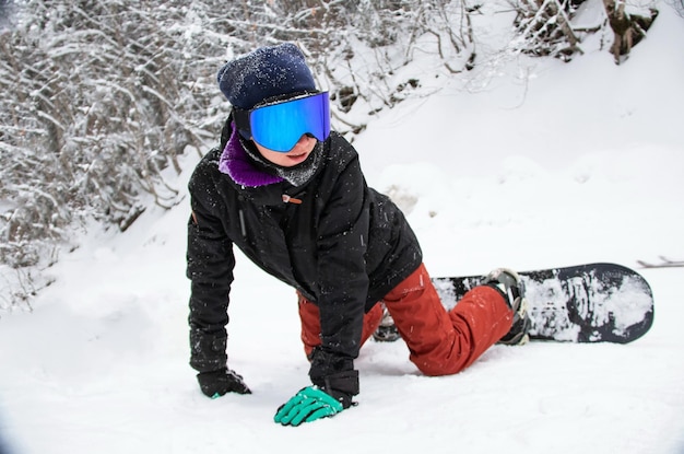 Una ragazza con uno snowboard si siede sul lato della montagna