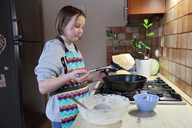 Una ragazza cucina le frittelle in cucina