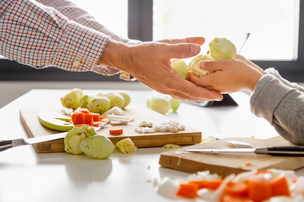 Una ragazza dà a suo padre una manciata di cavoletti di Bruxelles mentre cucina