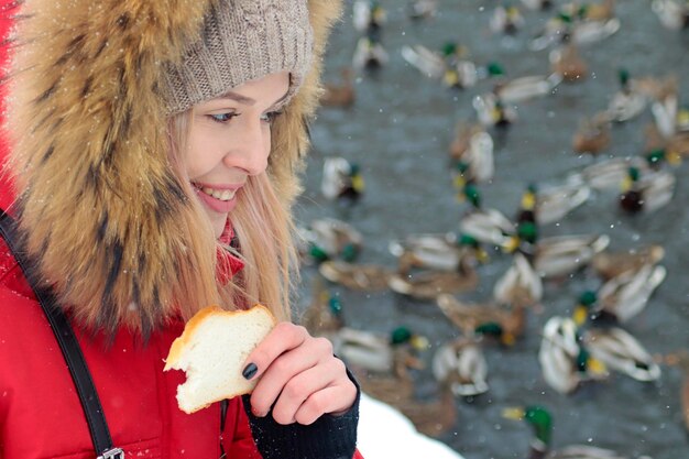 Una ragazza dà da mangiare agli uccelli in uno stagno in natura in inverno