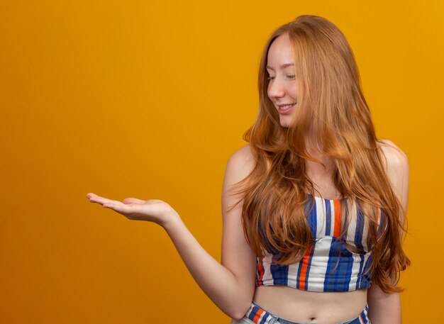 Una ragazza dai capelli rossi in giallo offre opportunità puntare il dito sul lato dello spazio libero copia per l'annuncio di contenuti promozionali.