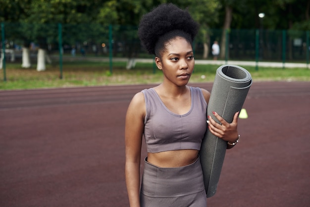 Una ragazza dalla carnagione scura si rilassa dopo un allenamento fitness in strada.