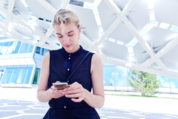 Una ragazza del futuro si siede sullo sfondo di un edificio futuristico, utilizza Internet mobile 5G