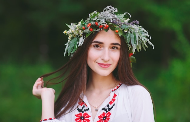 Una ragazza di aspetto slavo con una ghirlanda di fiori selvatici a metà estate.