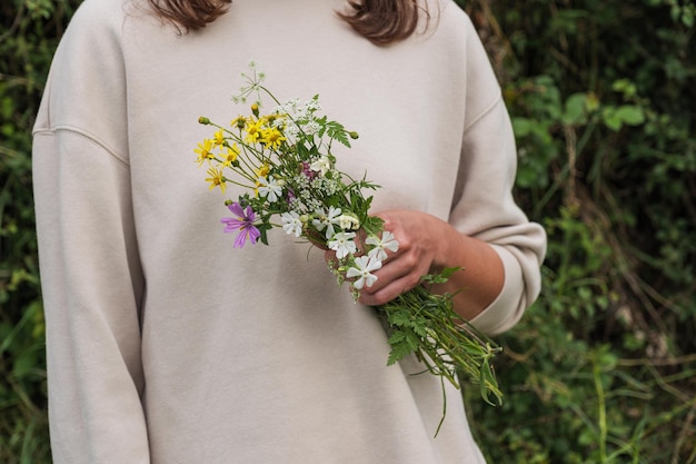 Una ragazza di campagna con una camicetta bianca che tiene in mano fiori di campo
