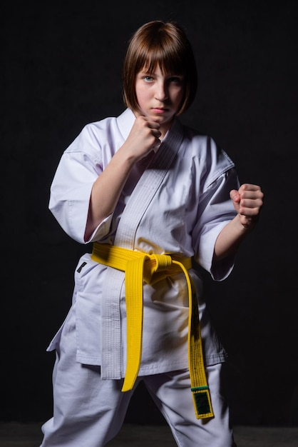 Una ragazza di karate si allena in un kimono con pugni e calci