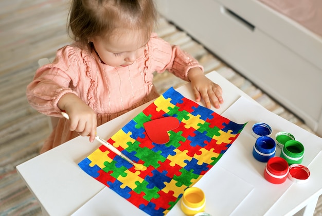 Una ragazza disegna un disegno da un puzzle colorato per il giorno della Giornata mondiale dell'autismo