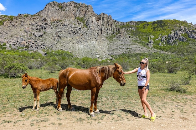 Una ragazza e cavalli sullo sfondo di antiche alte montagne in una foschia d'aria Demerji Crimea maggio 2021