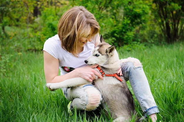 Una ragazza e il suo cane husky a piedi in un parco