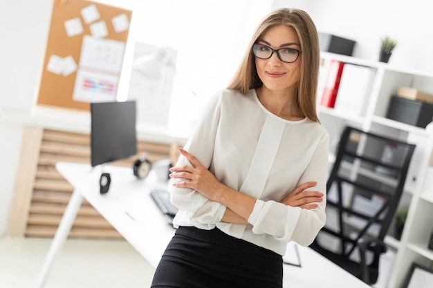 Una ragazza è in piedi appoggiata su un tavolo in ufficio.