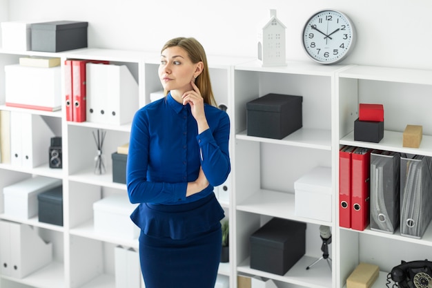 Una ragazza è in piedi in ufficio vicino allo scaffale.