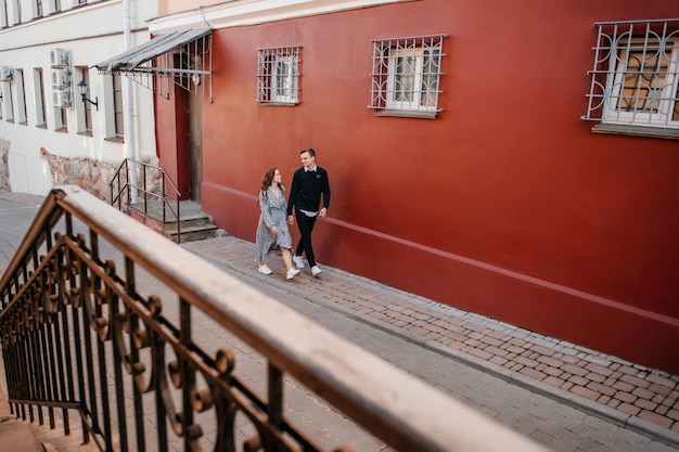 Una ragazza e un ragazzo stanno passeggiando per la città vicino al muro rosso