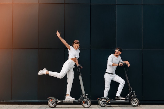 Una ragazza e un ragazzo stanno passeggiando su scooter elettrici per la città, una coppia innamorata in scooter.