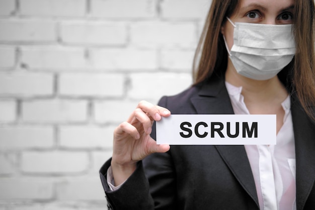 Una ragazza europea che indossa una mascherina medica tiene un cartello con la scritta Scrum