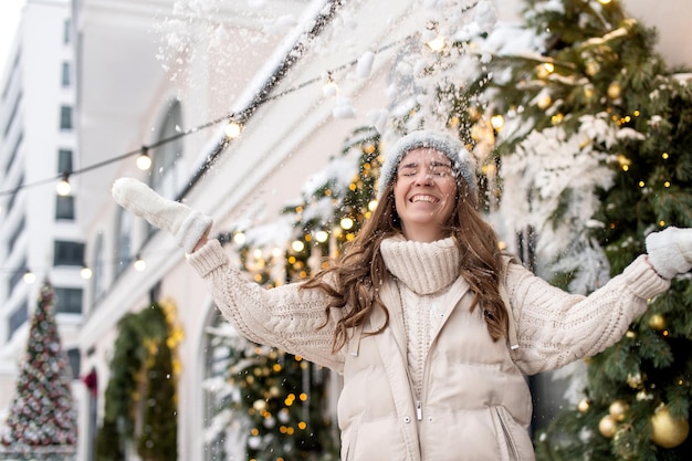 Una ragazza felice cammina per la città e lancia la neve