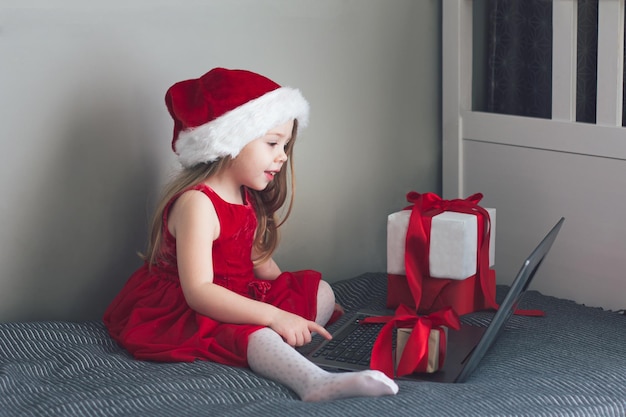 Una ragazza felice con un cappello da Babbo Natale rosso festivo