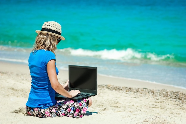 Una ragazza felice dell'uomo con il computer portatile vicino al viaggio di fine settimana al mare