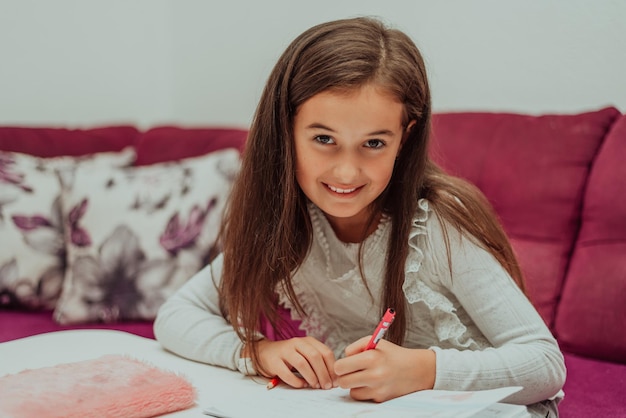 Una ragazza felice dello studente che fa i compiti a casa