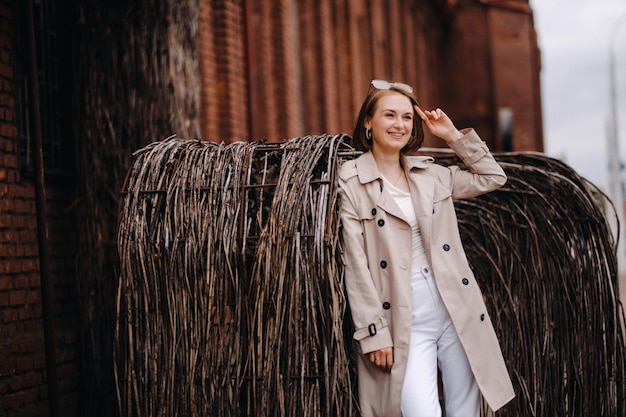 Una ragazza felice ed elegante con un cappotto grigio cammina per la città