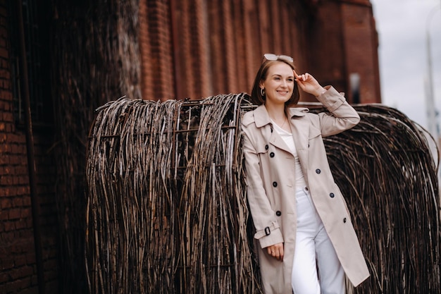Una ragazza felice ed elegante con un cappotto grigio cammina per la città