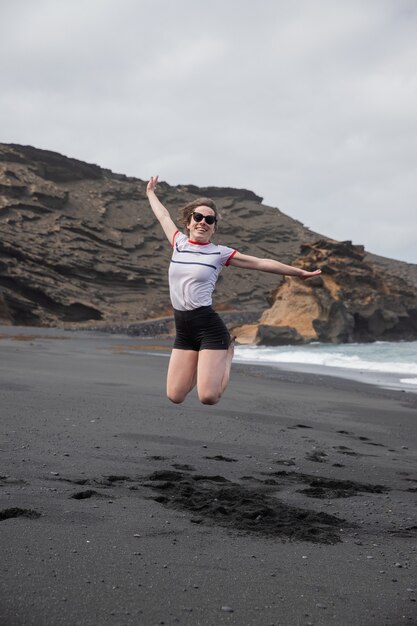 Una ragazza felice salta a braccia aperte in spiaggia si sta divertendo ed è entusiasta Concetto di felicità e libertà