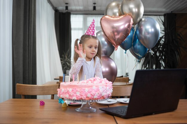 Una ragazza festeggia il suo compleanno via Internet durante la quarantena Arredamento festivo torta dolci palloncini Figlie con genitori festa per bambini